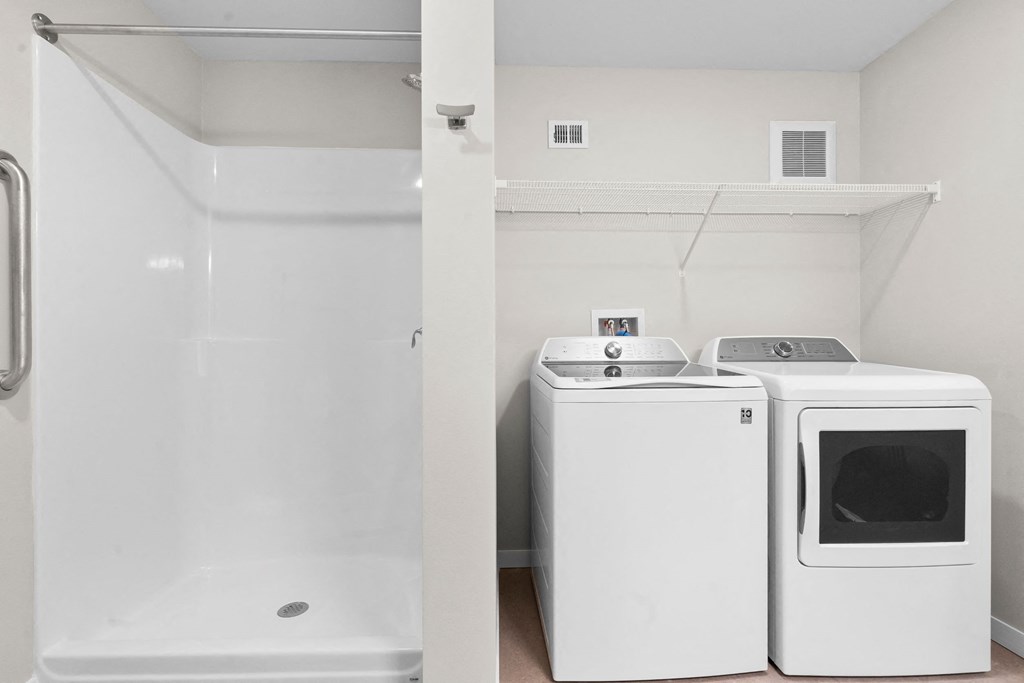 an empty laundry room with two washing machines and a shower