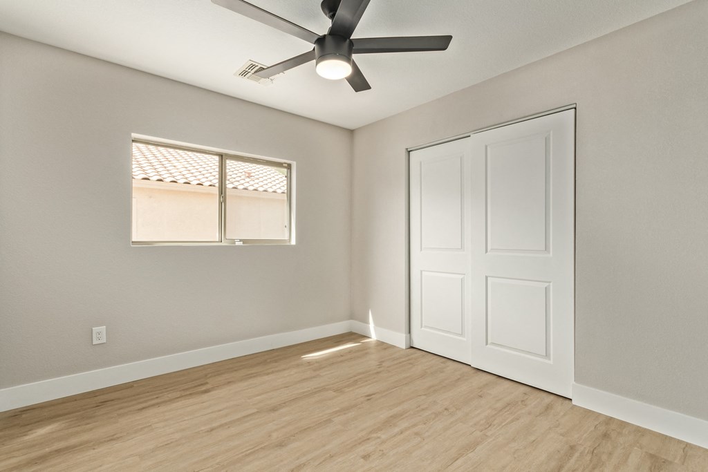 A room with a ceiling fan and a window with blinds.