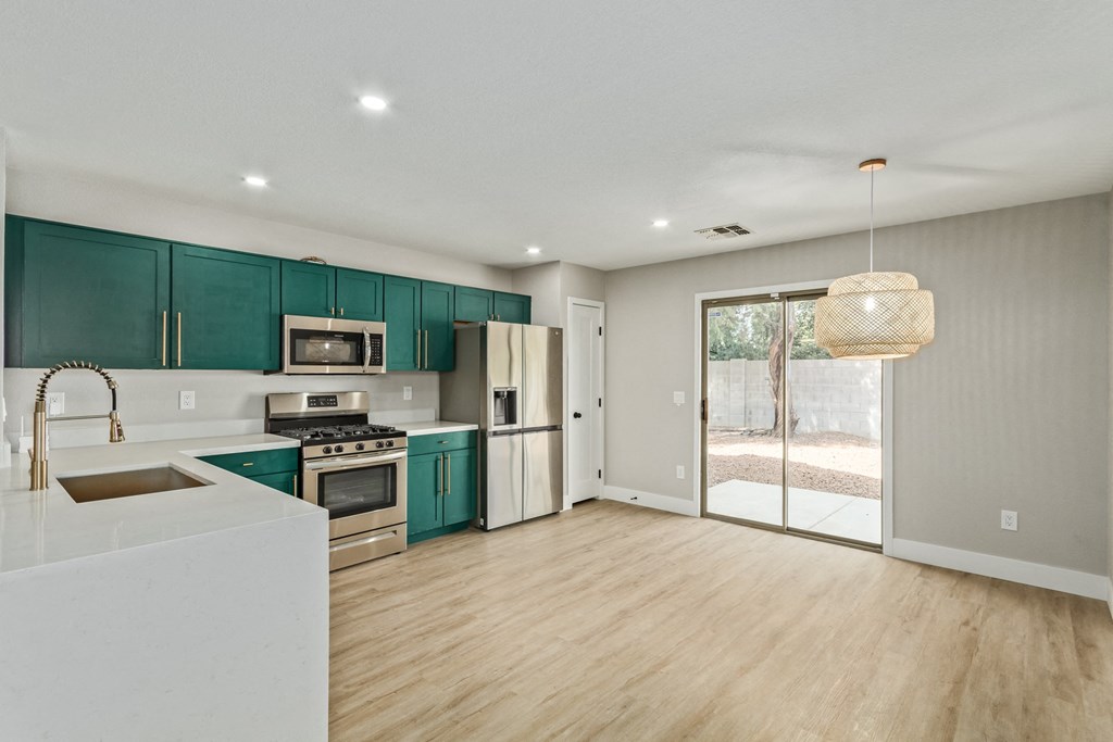 A modern kitchen with teal cabinets and stainless steel appliances.