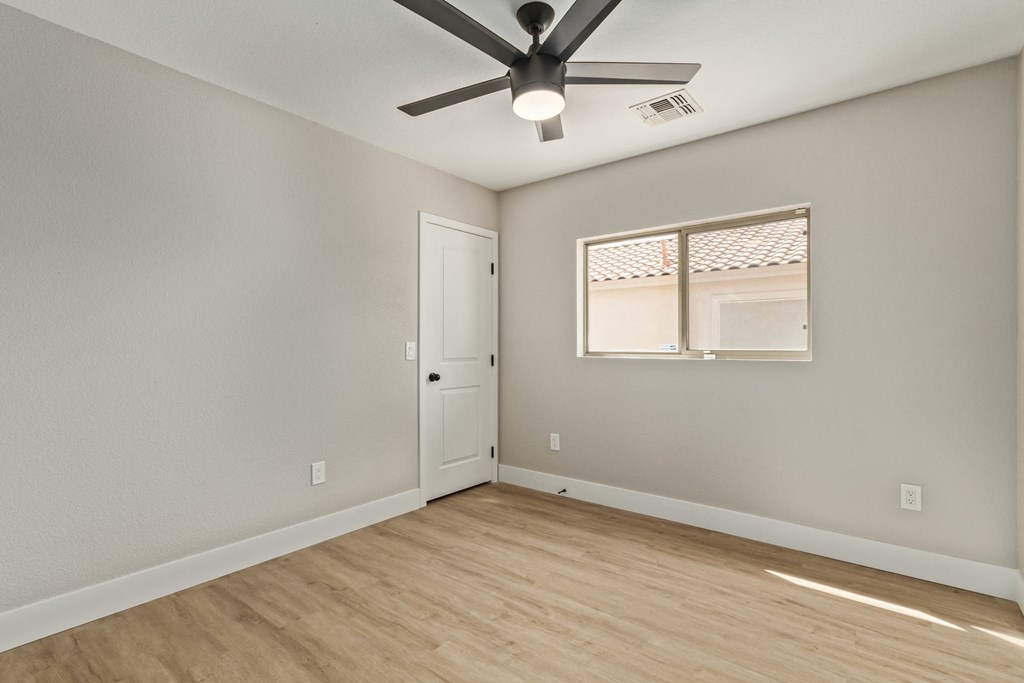 A room with a ceiling fan and a window with blinds.