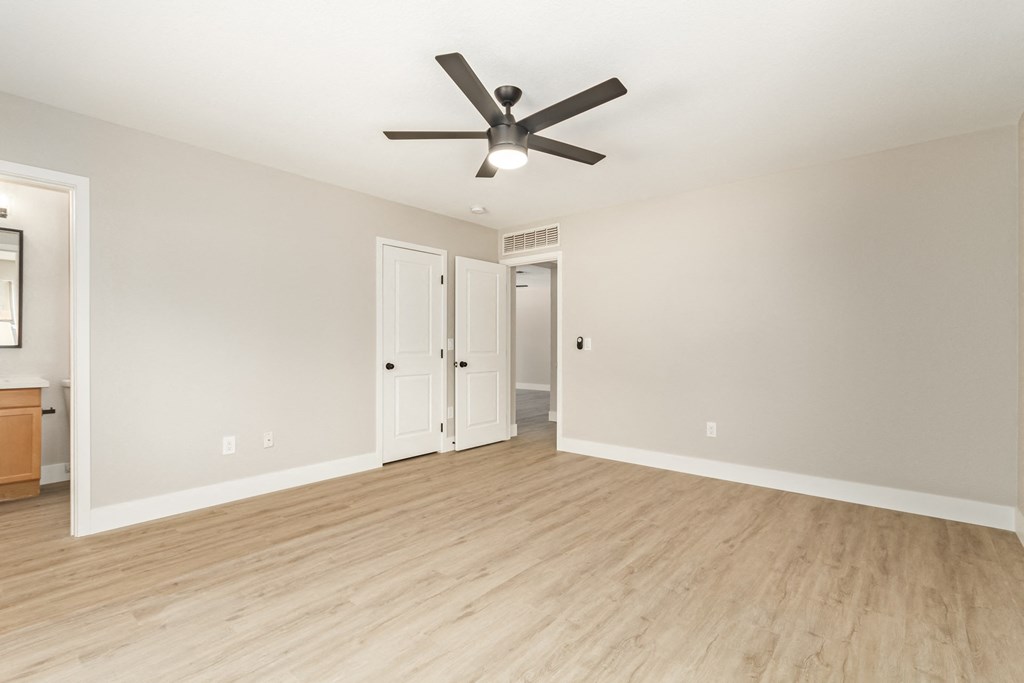 A room with a ceiling fan and wooden flooring.