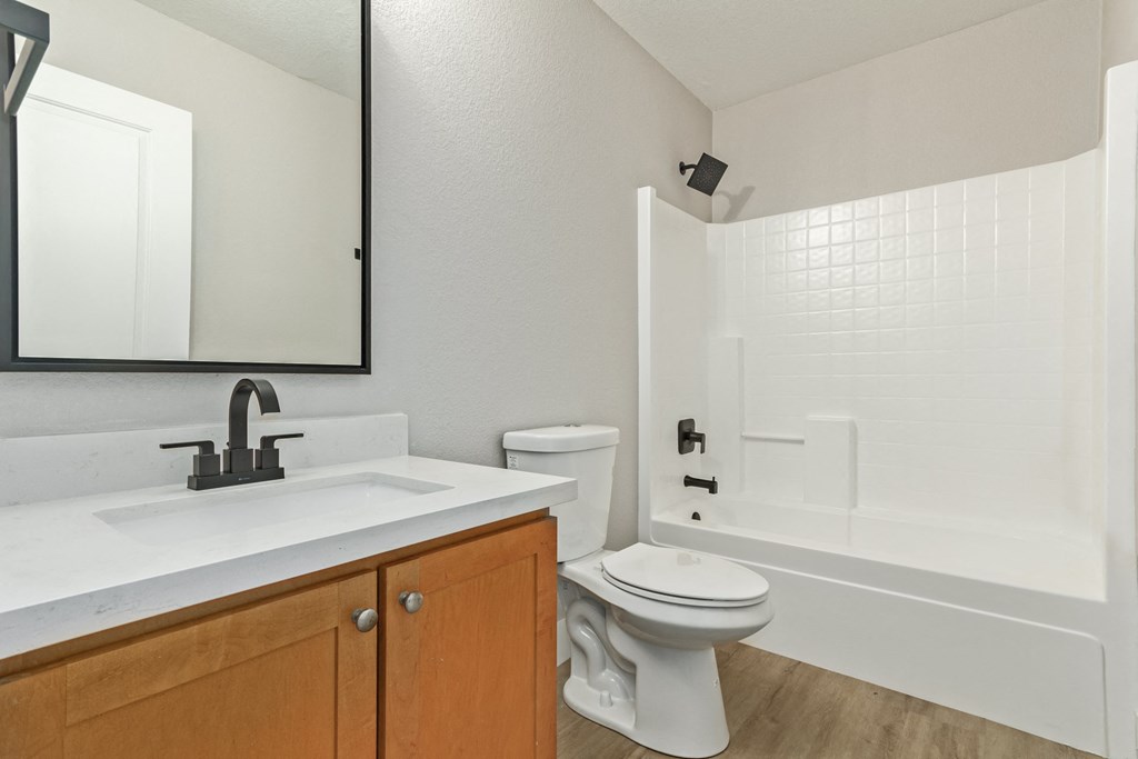 A white toilet is in a bathroom with a sink and mirror.