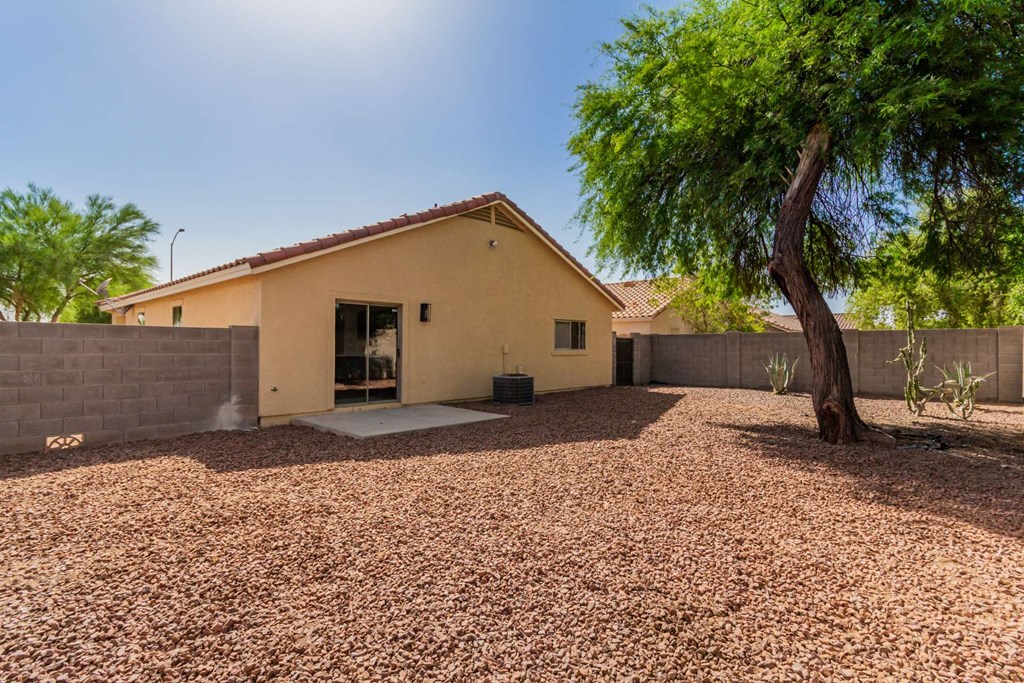 A house with a gravel driveway and a tree in front.
