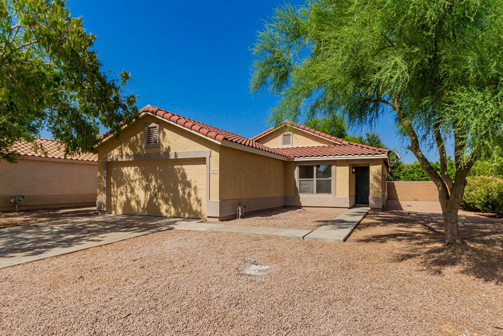 A house with a red tile roof and a tree in front.