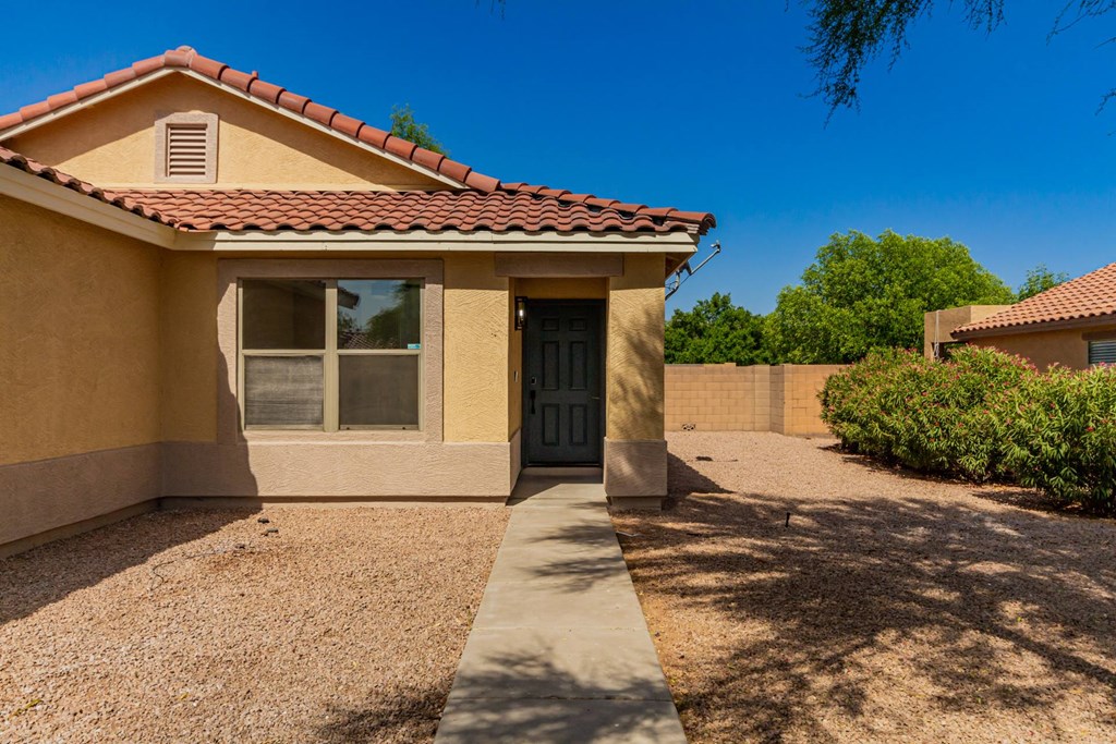 A house with a brown roof and tan walls with a black door and window.
