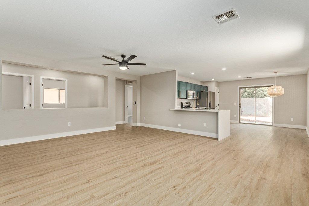 A spacious room with a ceiling fan and lighting fixtures.