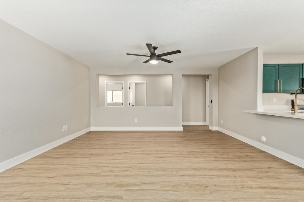 A room with a ceiling fan and wooden flooring.