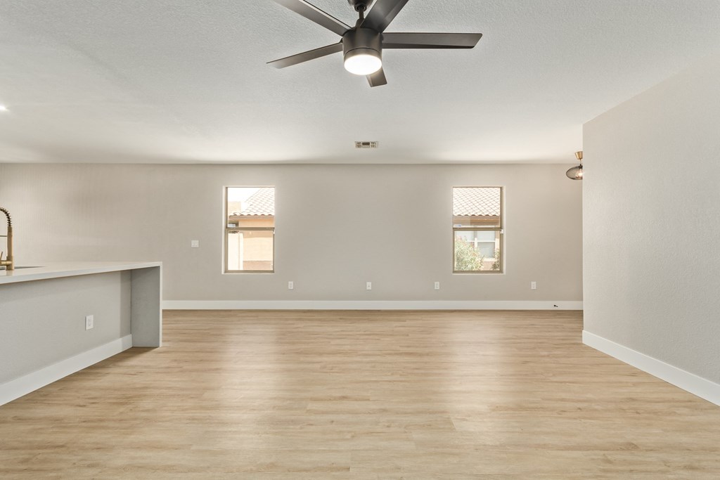 A spacious room with a ceiling fan and wooden flooring.