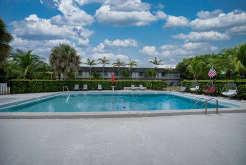 a swimming pool in front of a hotel with palm trees