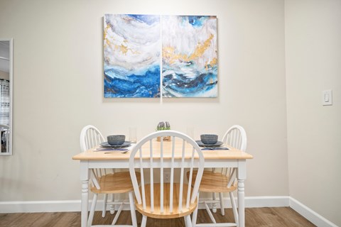 a dining room with a table and chairs and two paintings on the wall