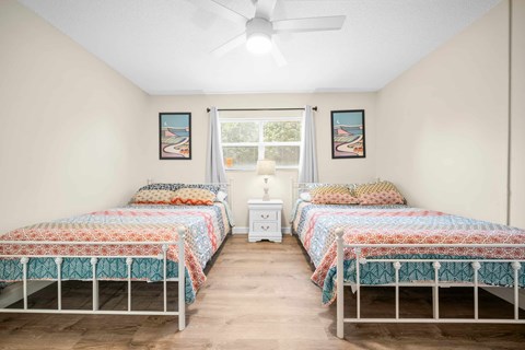 a bedroom with two beds and a ceiling fan