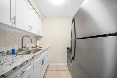 a kitchen with white cabinets and a stainless steel refrigerator