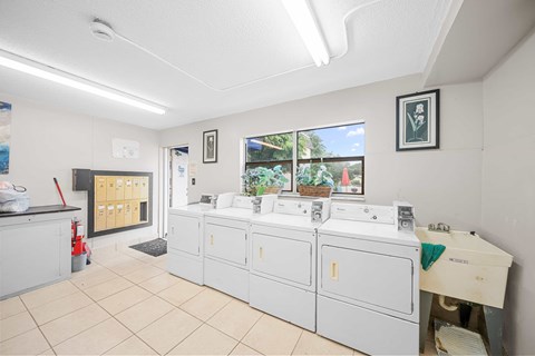 a laundry room with a row of white washers and dryers