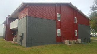 a large red and black barn with a gray brick wall