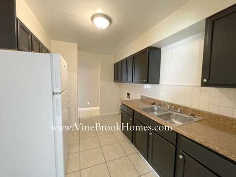 A kitchen with black cabinets and a white refrigerator.