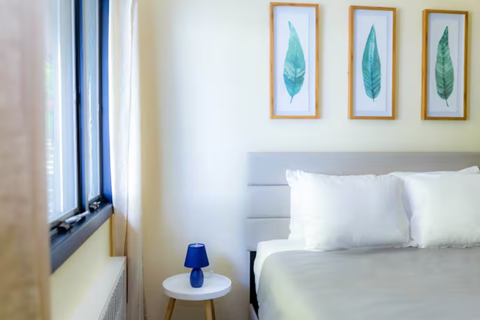 a small bedroom with a bed and two paintings on the wall