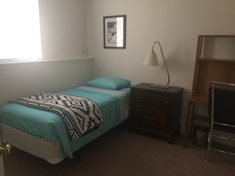 A bedroom with a bed, nightstand, and a lamp.
