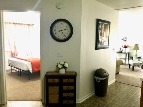 A bedroom with a bed, nightstand, and a clock on the wall.