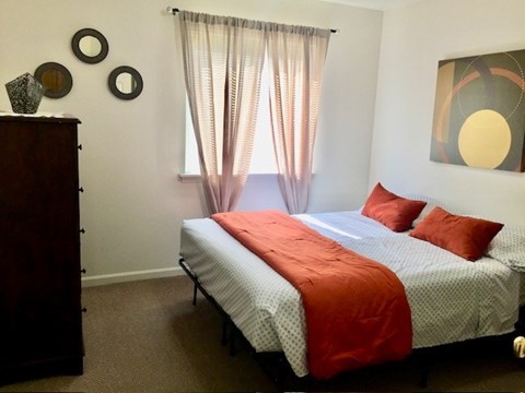 A bedroom with a bed, a dresser, and a painting on the wall.