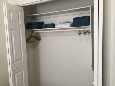 A white closet with a hanger and two boxes on the shelf.