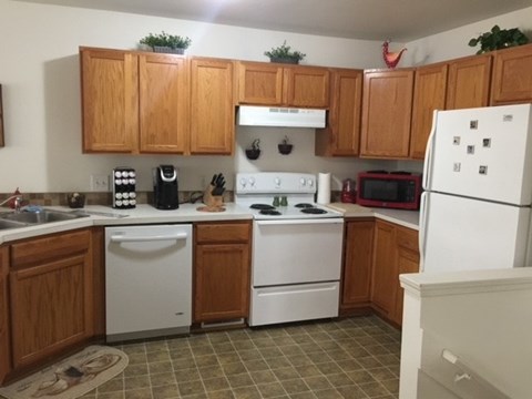 A kitchen with white appliances and wooden cabinets.