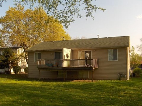 A house with a balcony and a tree in the background.