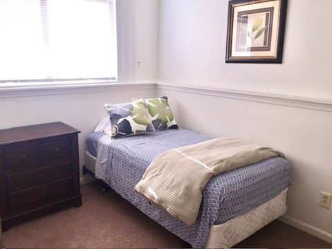 A bed with a blue and white comforter and a white blanket on it.
