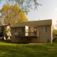 A house with a balcony is surrounded by a green lawn.