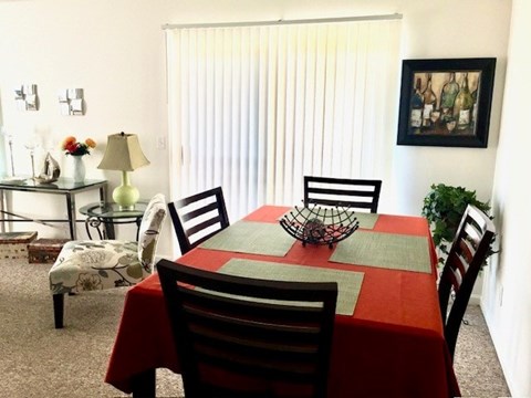A dining room with a red tablecloth and chairs.