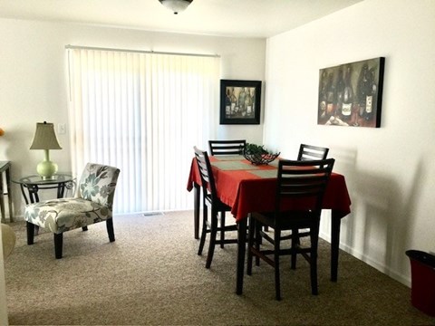A dining room with a table set for two and a painting on the wall.