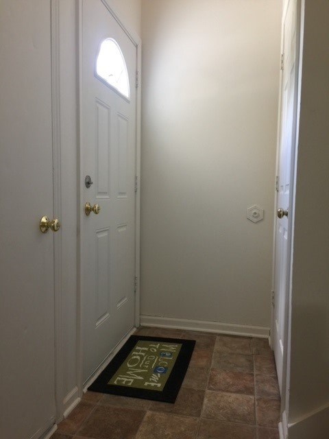 A hallway with a white door and a doormat that says "welcome".