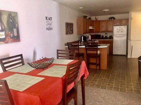 A dining room with a red tablecloth and wooden chairs.