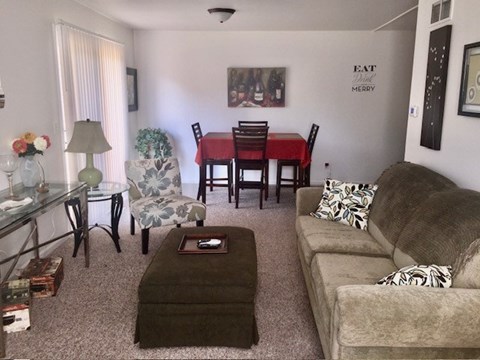 A living room with a couch, chairs, and a dining table.