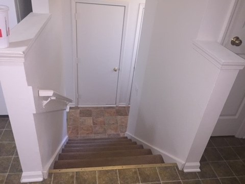 A white door is in a hallway with a tiled floor.