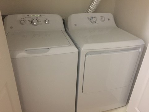 Two white front loading washing machines in a small room.