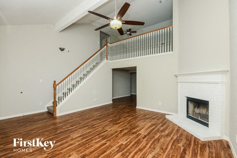 A spacious living room with a fireplace and a ceiling fan.