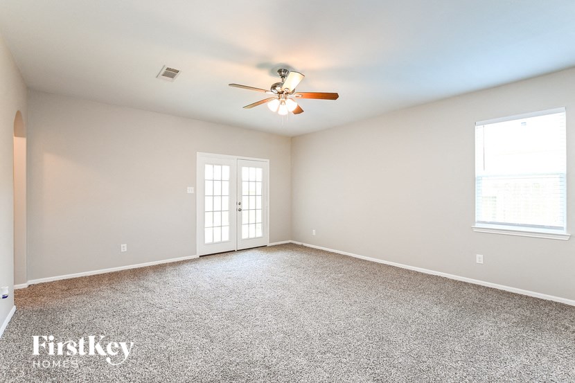 a empty living room with a ceiling fan and a window