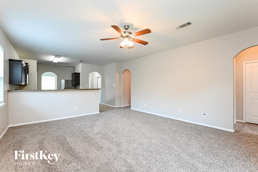 an empty living room with carpet and a ceiling fan