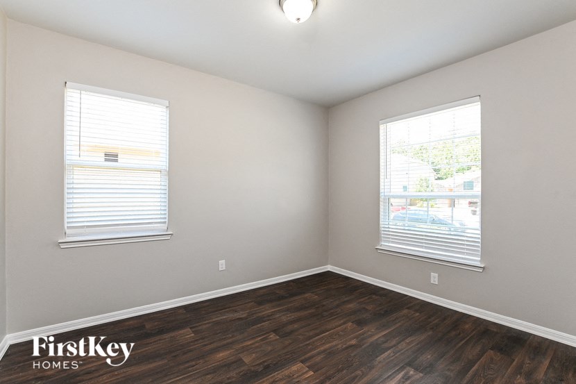 the living room of a home with wood flooring and two windows