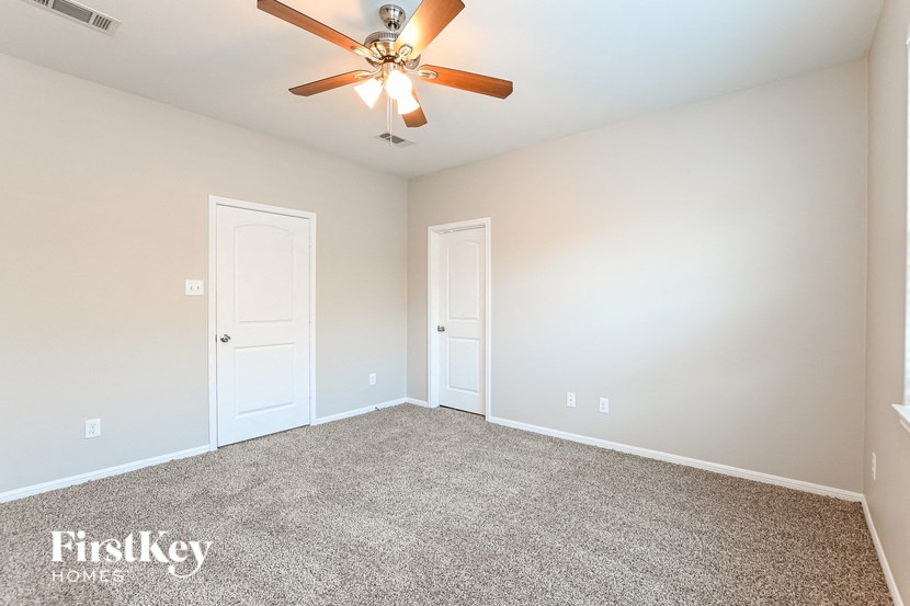 the spacious living room with ceiling fan and carpet