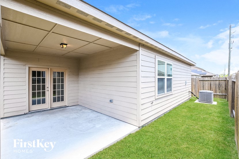 a patio in front of a white house with a lawn