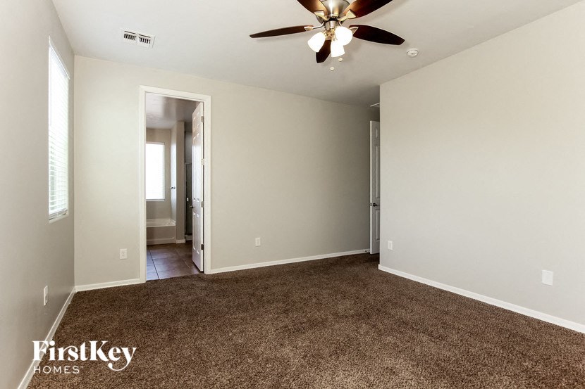 an empty living room with a ceiling fan and a carpet