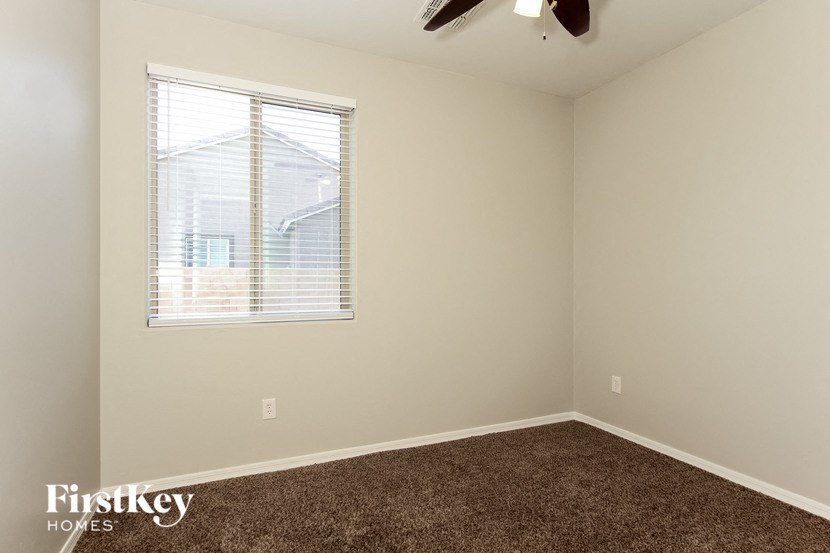 an empty room with a window and a brown carpet