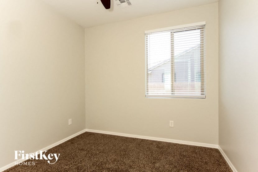 an empty room with a window and a brown carpet