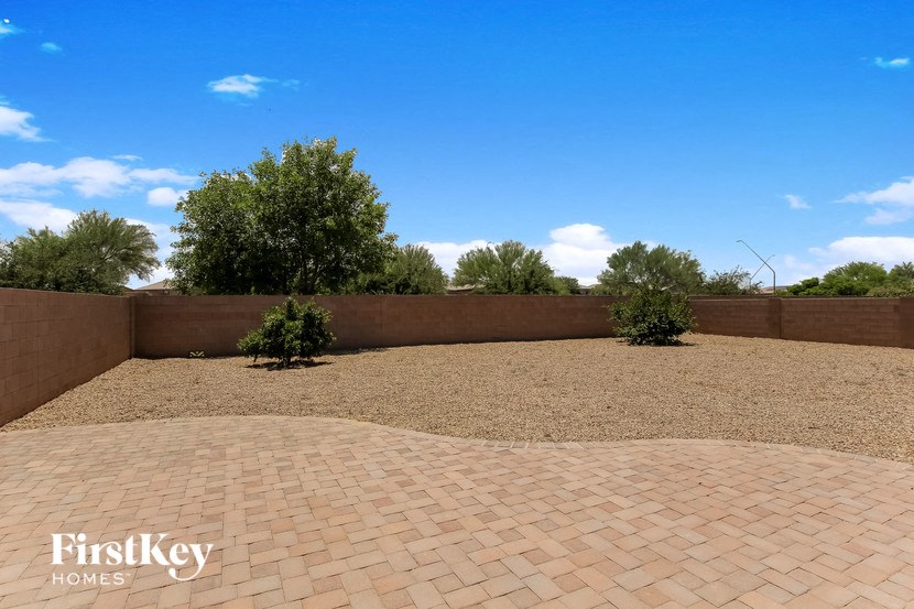 the backyard of the house has a brick patio and two bushes