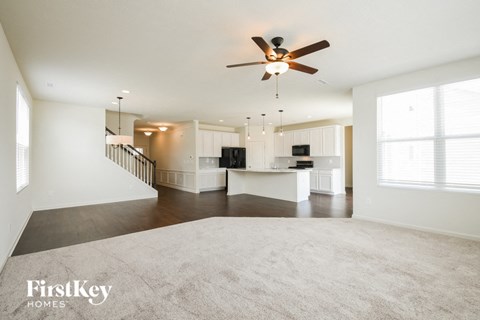 an empty living room and kitchen with a ceiling fan