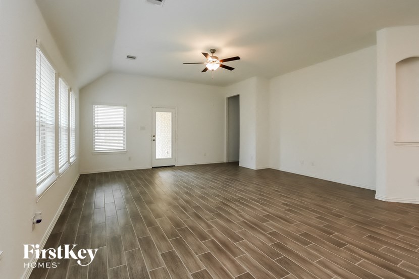 an empty living room with wood floors and a ceiling fan