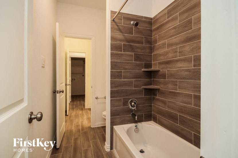 a bathroom with a tub and a shower and a hallway with a door