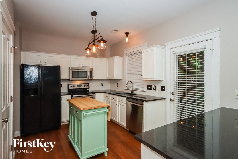 a kitchen with white cabinets and black appliances and a green cabinet