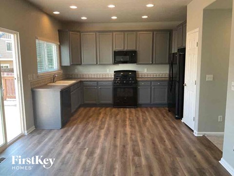 A kitchen with wooden floors and a black fridge.